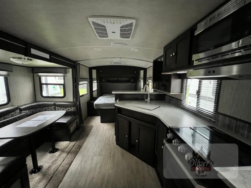 Used 2019 Cruiser Shadow Cruiser 225RBS interior view of the kitchen, U-shaped dinette, and queen bed in the front of the RV